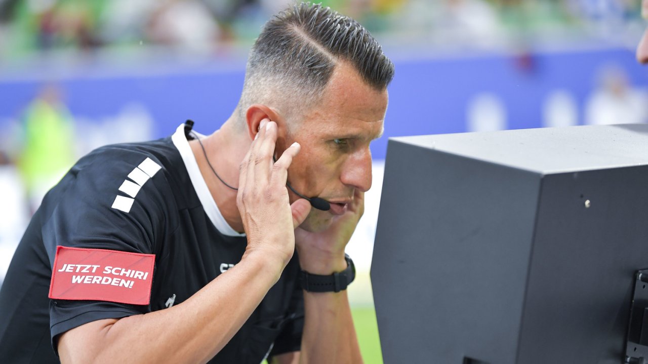 Schiedrichter Alexander Harkam im Austausch mit dem VAR